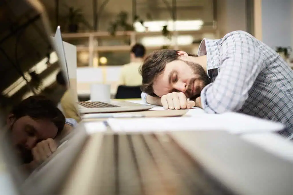 Relaxed man resting at work desk, emphasizing energy awareness for writers.