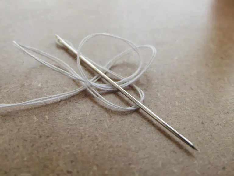 Sewing needle with loose thread on paper, symbolizing creative flow and storytelling.