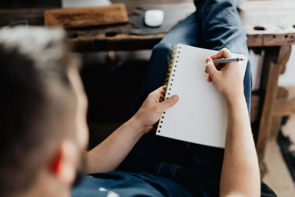 Person writing in a notebook, practicing the Law of Attraction for writers.